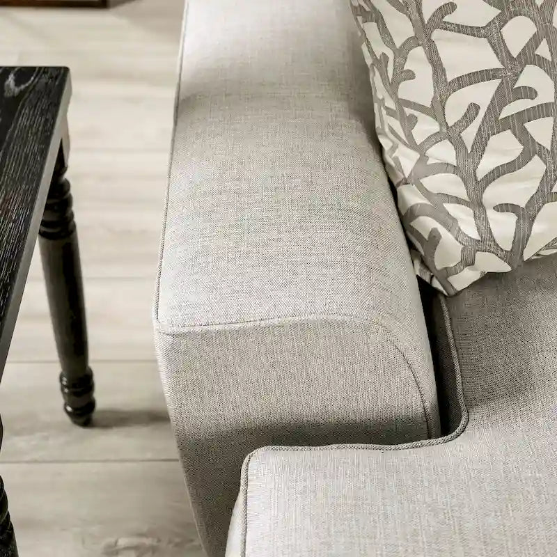 Canapé en tissu gris clair de style transitoire bleu, avec garniture cloutée et coussins décoratifs.
