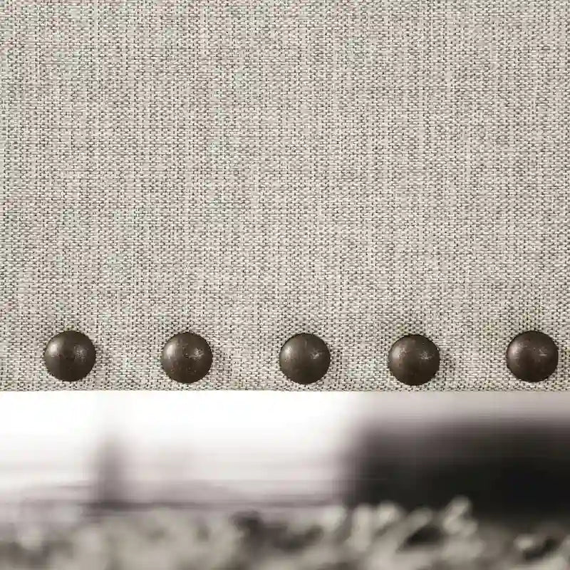 Canapé en tissu gris clair de style transitoire bleu, avec garniture cloutée et coussins décoratifs.